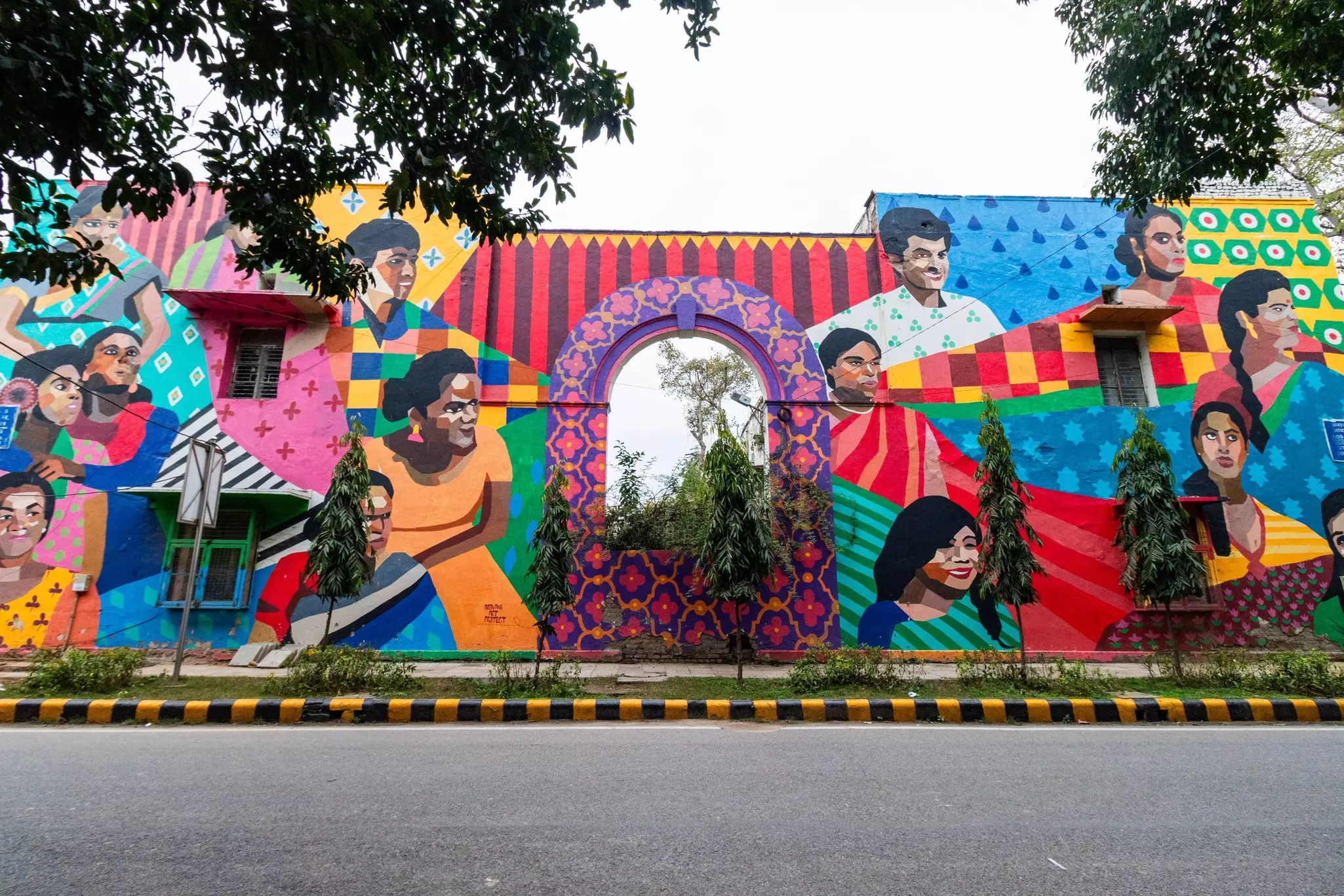 A vast wall painted in bright colors with murals of men an women.