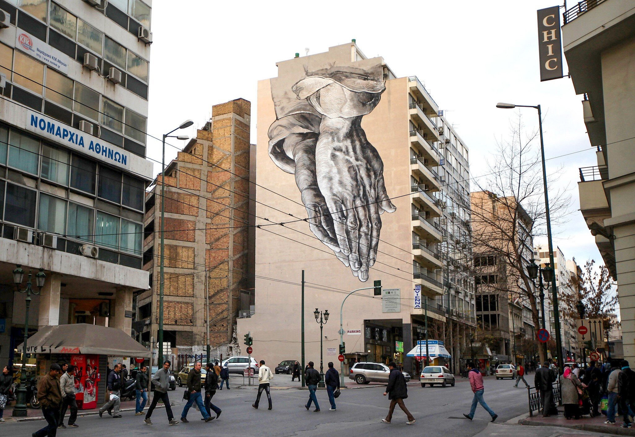 ATHENS, GREECE - FEBRUARY 18: Members of the public walk beneath a giant mural based on Albrecht Durer's 'Praying Hands' on February 18, 2012 in Athens, Greece. Following a meeting on Wednesday, finance ministers across the Eurozone are calling fo...