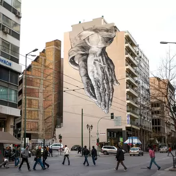 ATHENS, GREECE - FEBRUARY 18: Members of the public walk beneath a giant mural based on Albrecht Durer's 'Praying Hands' on February 18, 2012 in Athens, Greece. Following a meeting on Wednesday, finance ministers across the Eurozone are calling fo...
