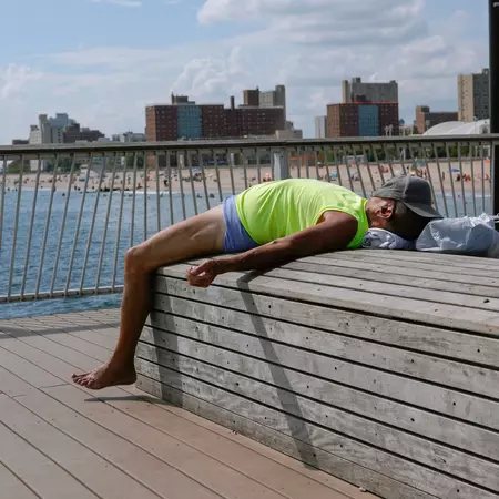 A man is sunbathing on a bench on the Coney Island pier. A hot summer in New York City