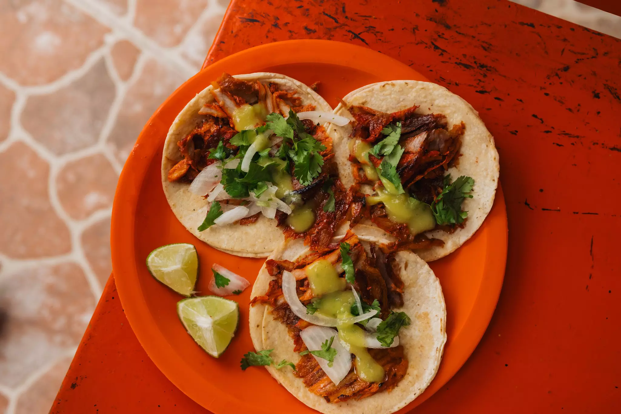 An overhead shot of a plate of al pastor tacos.