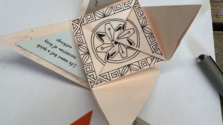 Folded ecru paper with a black design on the border and in the center.