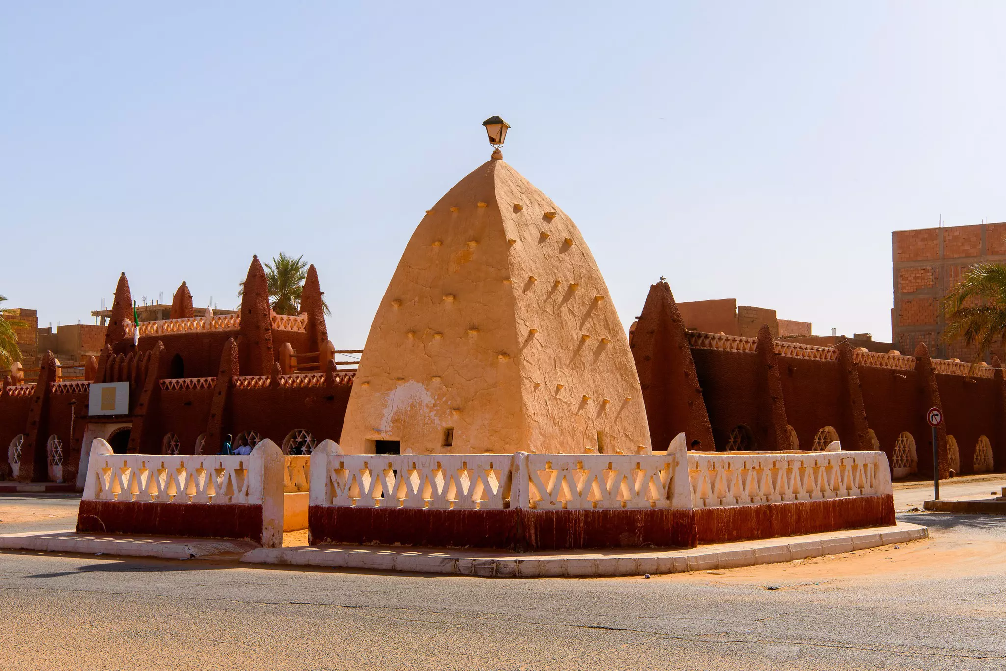 A domed structure surrounded by a low fence with a walled area behind it in Algeria.
