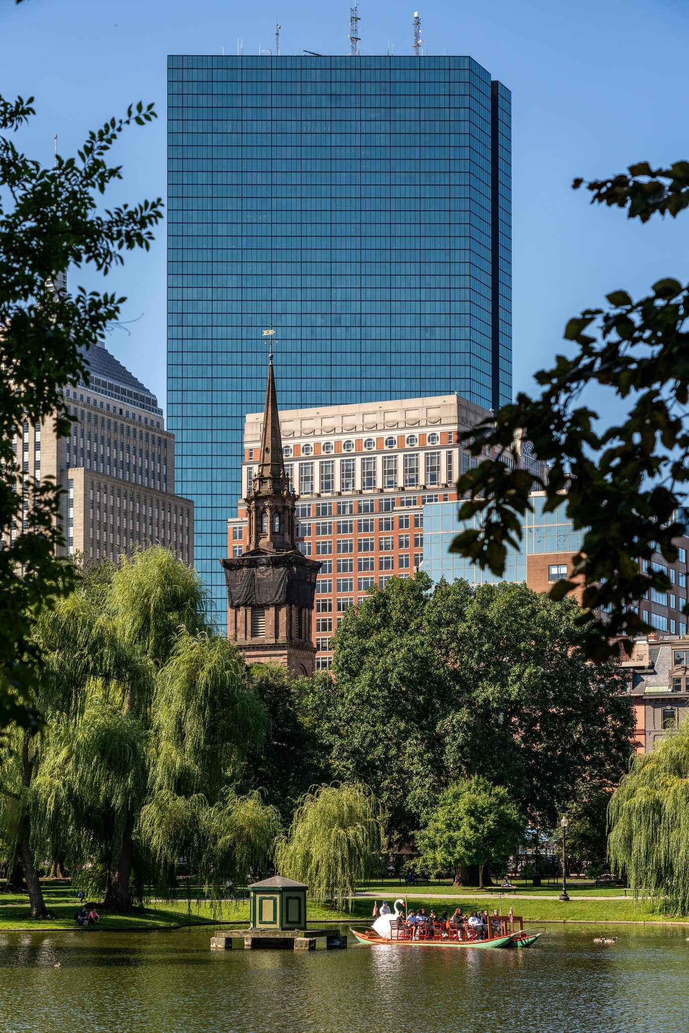 View of the city skyline on a sunny day as seen from across the pond in the Public Garden in Boston, Massachusetts.