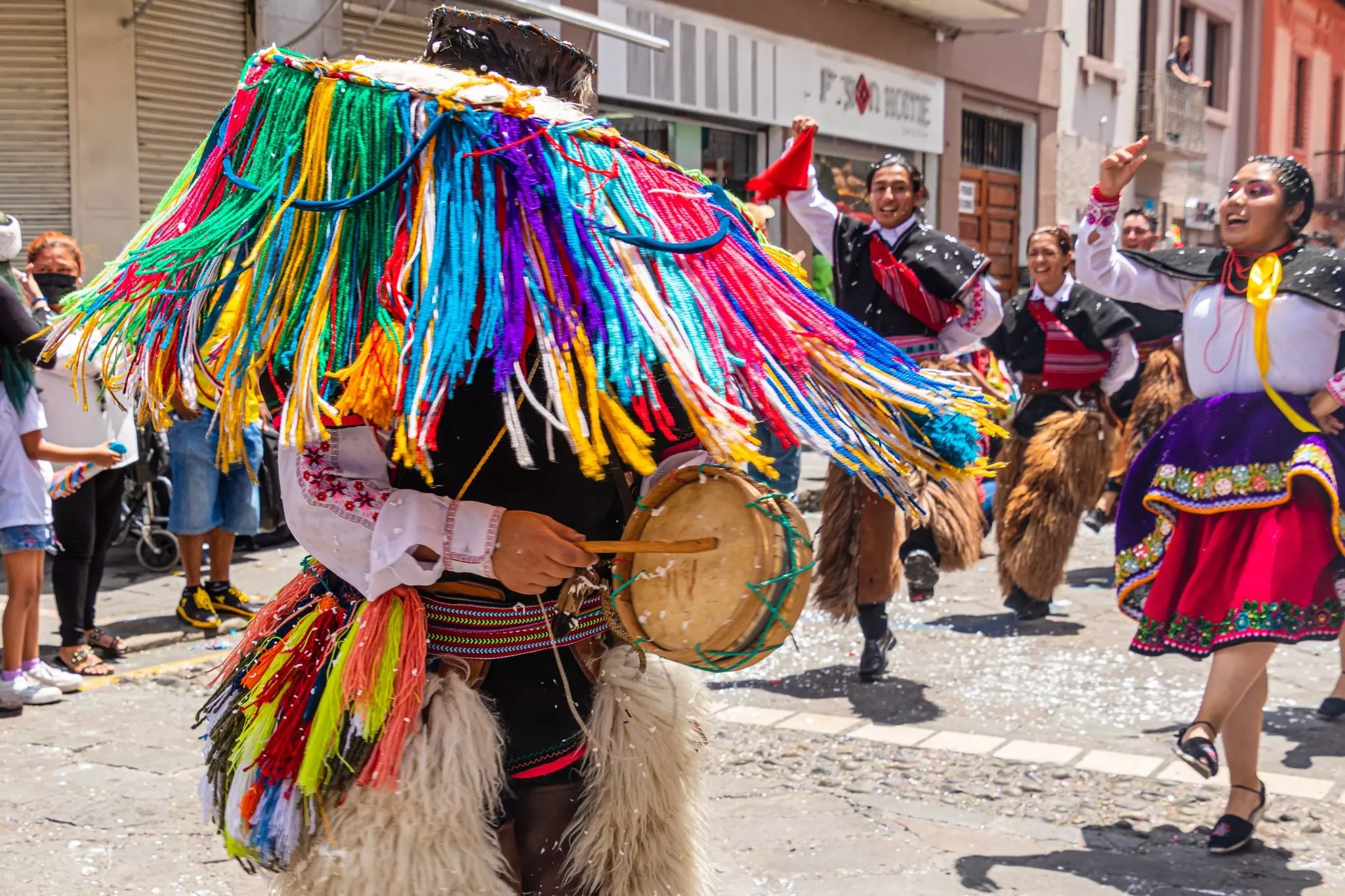 Folk dancers of the Azuay province in the historical center of Cuenca, with bits of foam on the dancers, on the floor and in the air