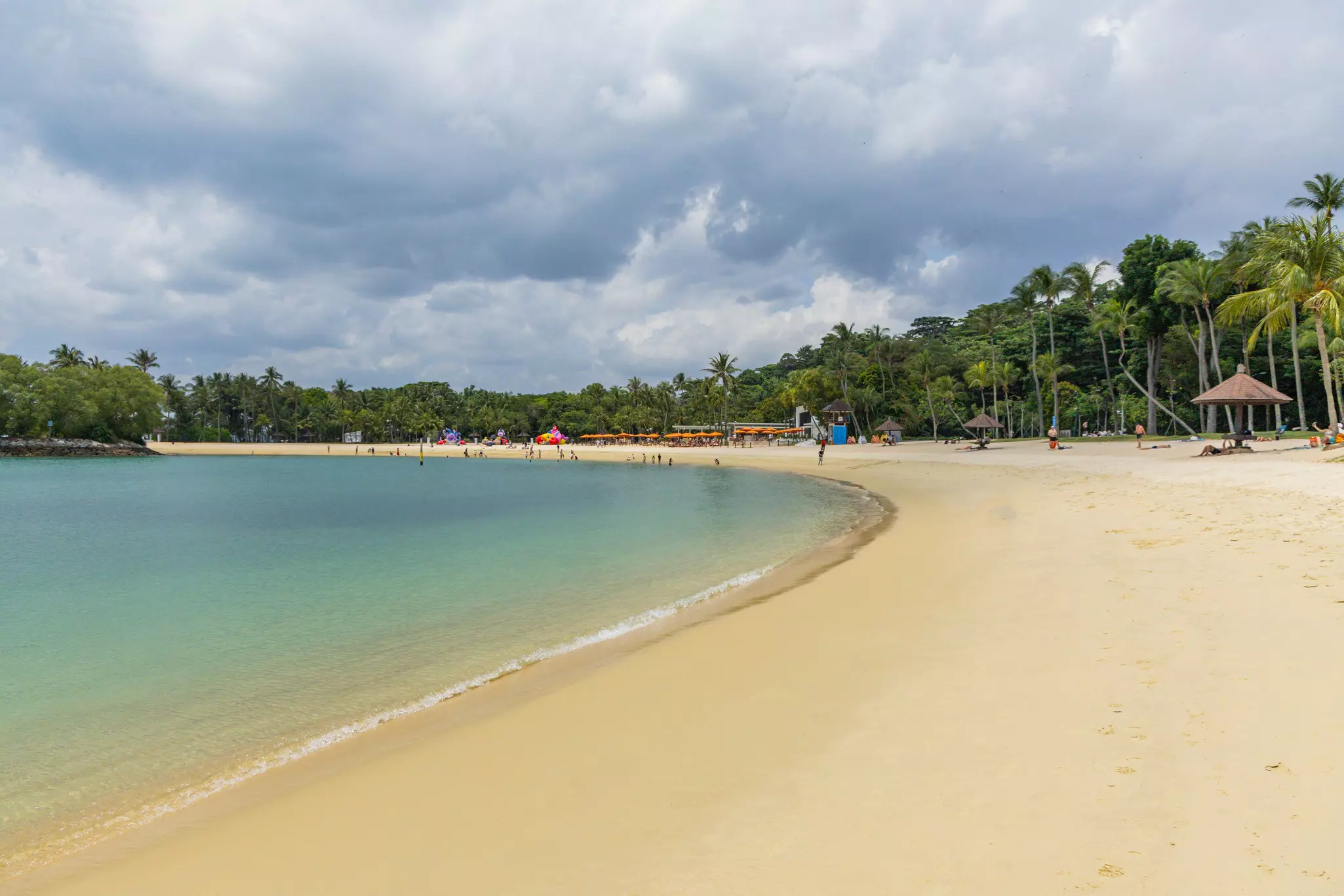 A long curve of golden sand with a row of sunshades.