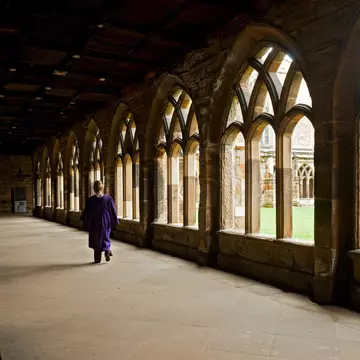 A person walks down a corridor in the cloisters of Durham Cathedral, Durham, England, United Kingdom