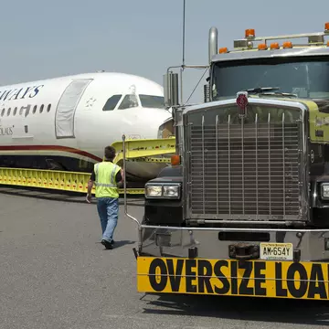 A plane on a massive truck as it is moved to a museum.