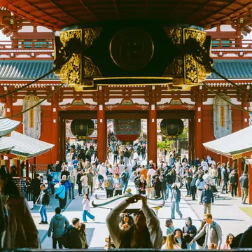 Crowds of people are pictured in the pagoda-covered pavilion of a temple.