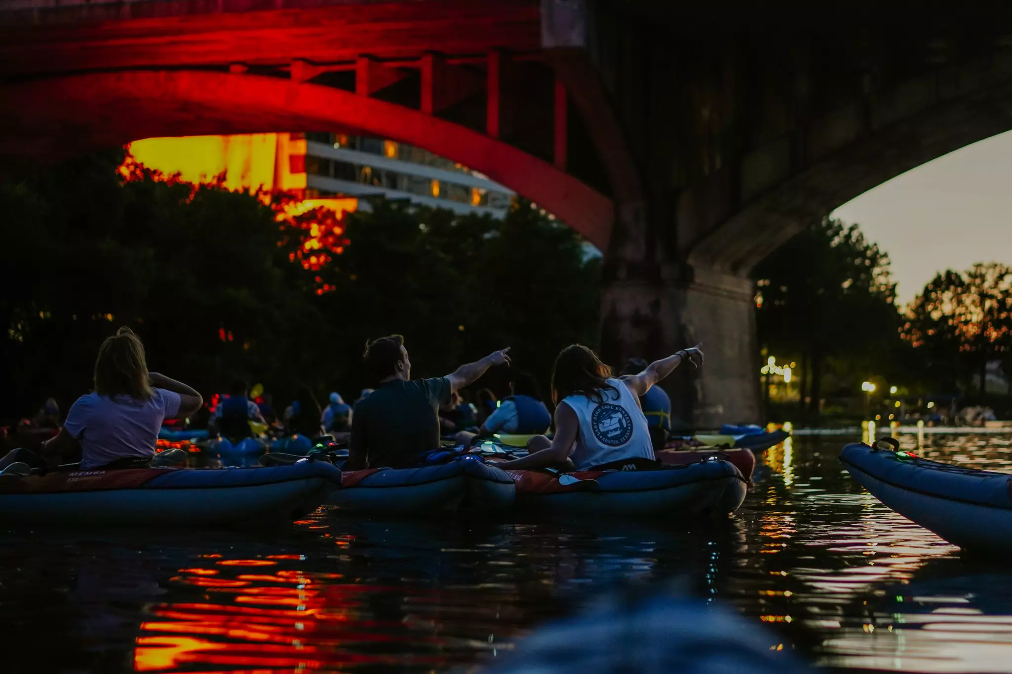 Kayakers at sunset pointing toward a bridge