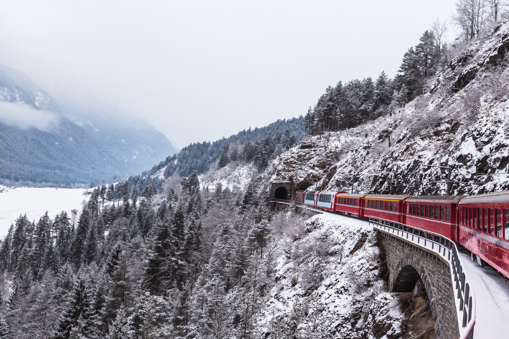 A train enters a tunnel in a snowy landscape.