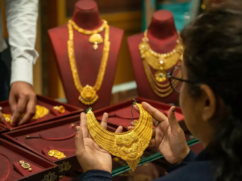 Woman holding a gold necklace. 