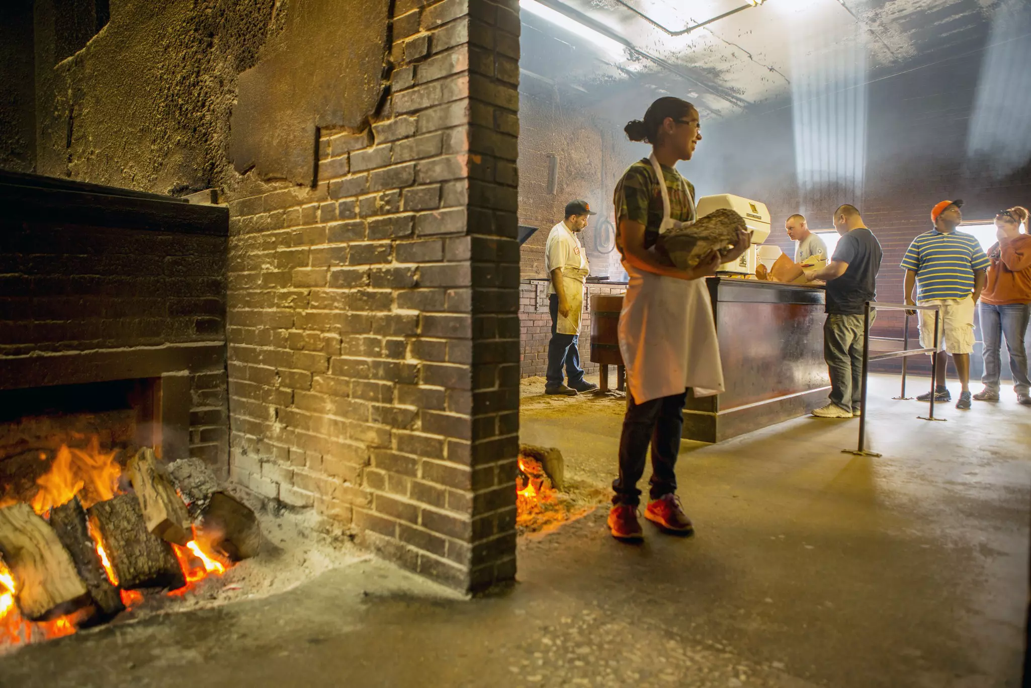 A worker with firewood for the never-ending barbecue fire at Smitty's Market in Lockhart, Texas © Kris Davidson / Lonely Planet