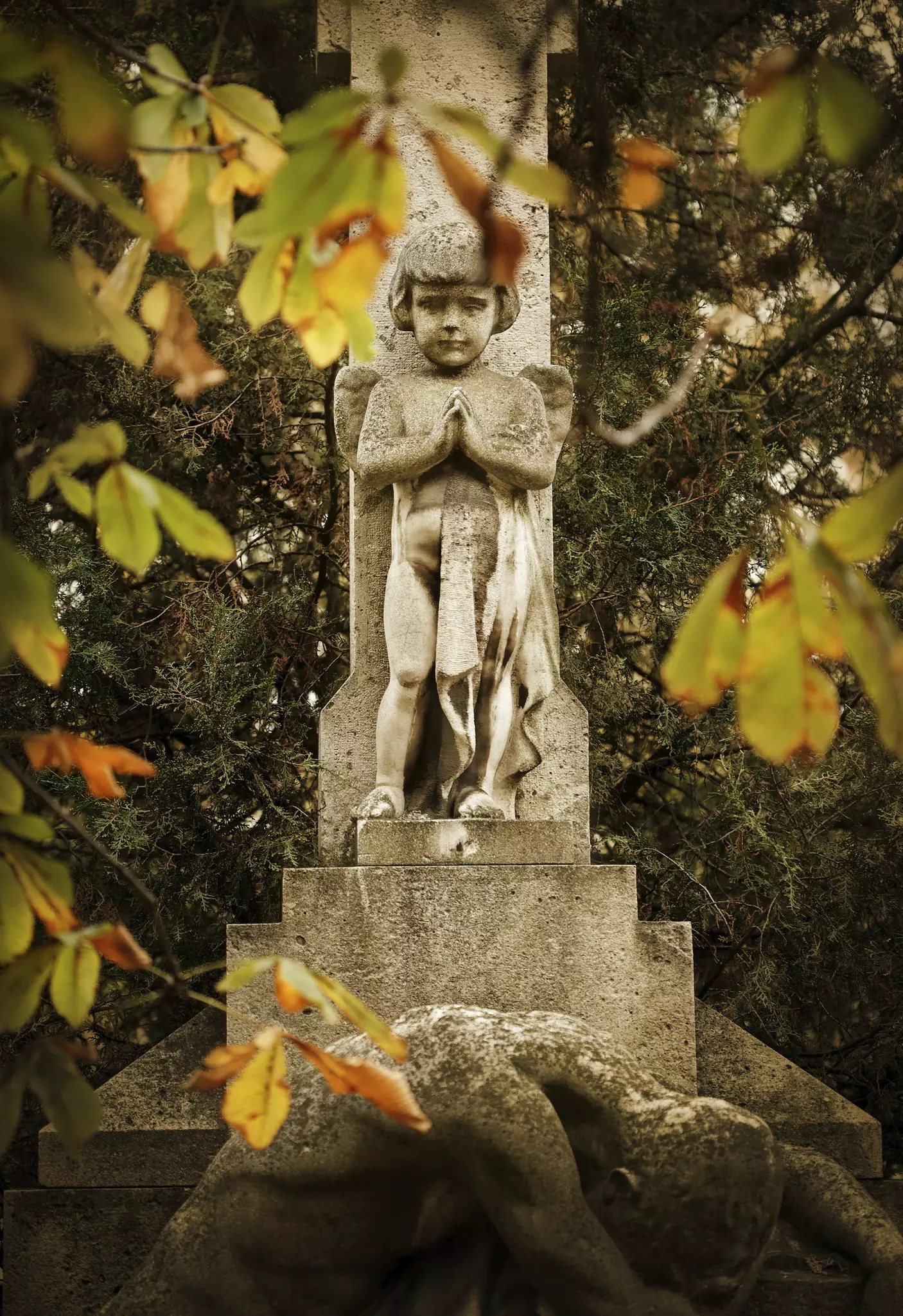 A closeup of statue of a women's face and upper body in front of a mausoleum at the Kerepesi Cemetery; Budapest autumn