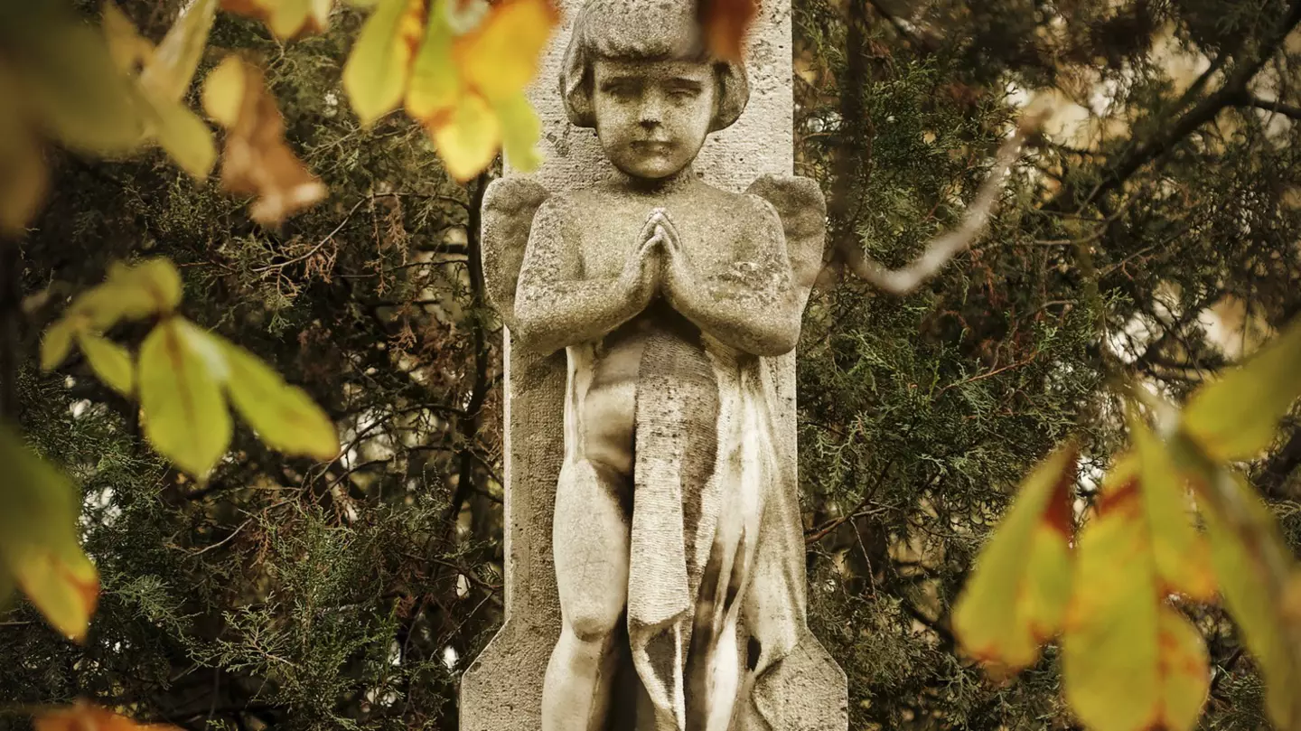 A closeup of statue of a women's face and upper body in front of a mausoleum at the Kerepesi Cemetery; Budapest autumn