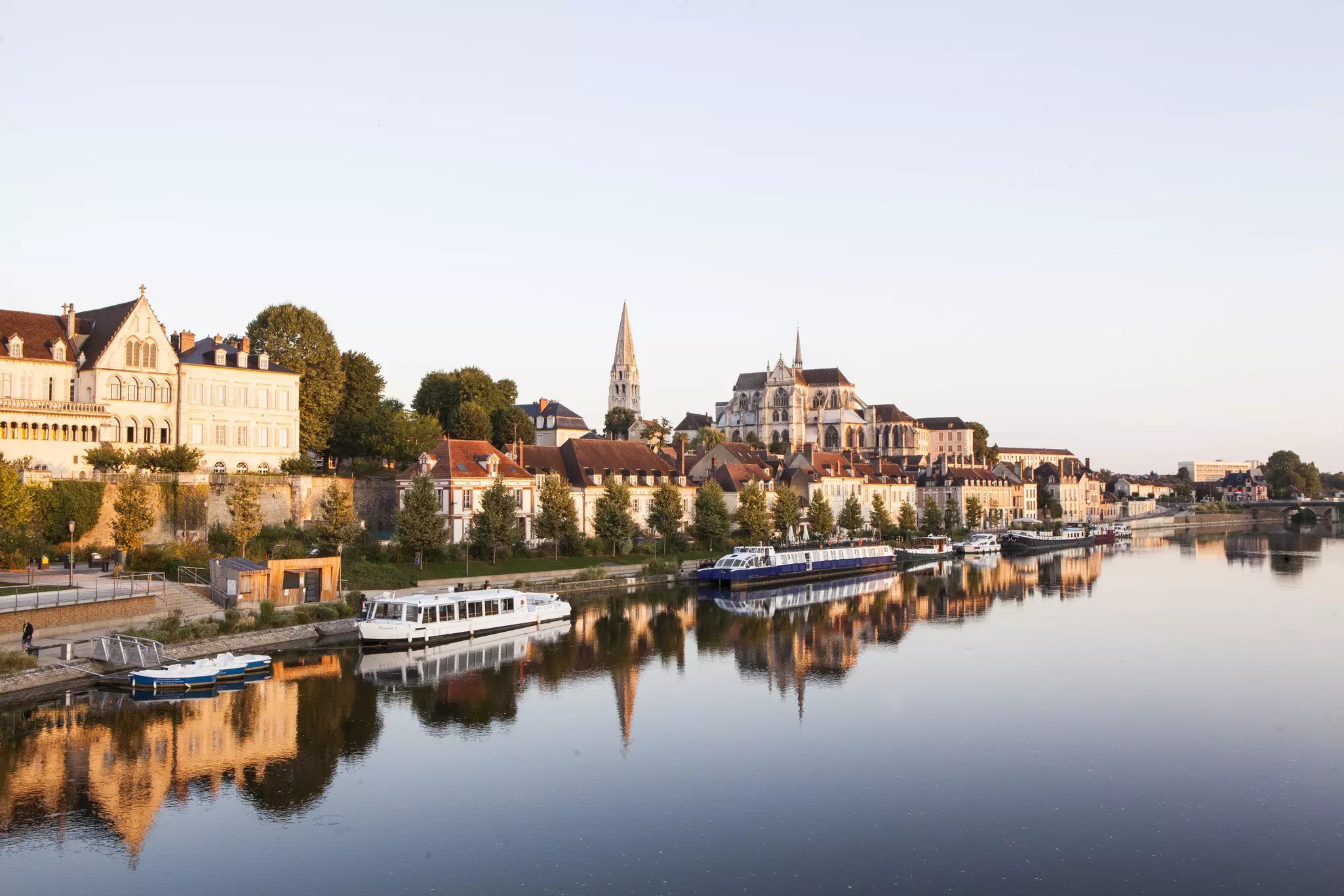 A small riverside town with a large abbey near the water glowing in the setting sun.