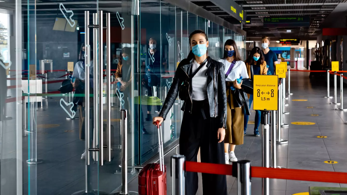 Passengers wearing N95 face masks waiting in line at airport terminal