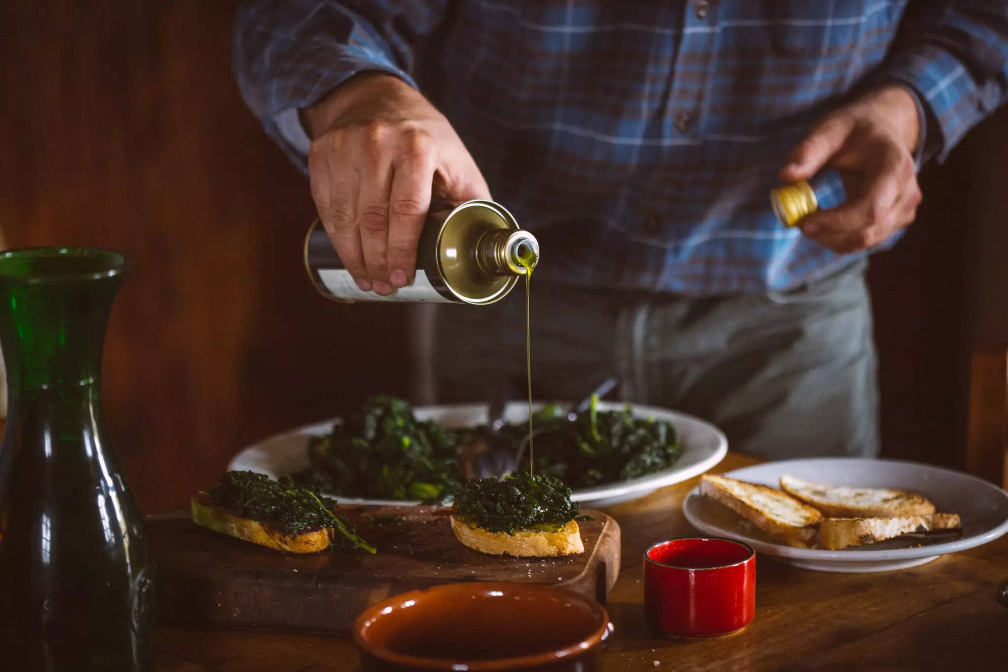 Man pouring olive oil over Tuscan bruschetta and cavolo nero
