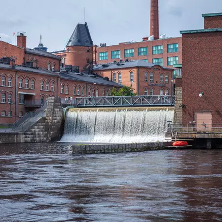 Water rushes through a sluice by red brick buildings in Finland.