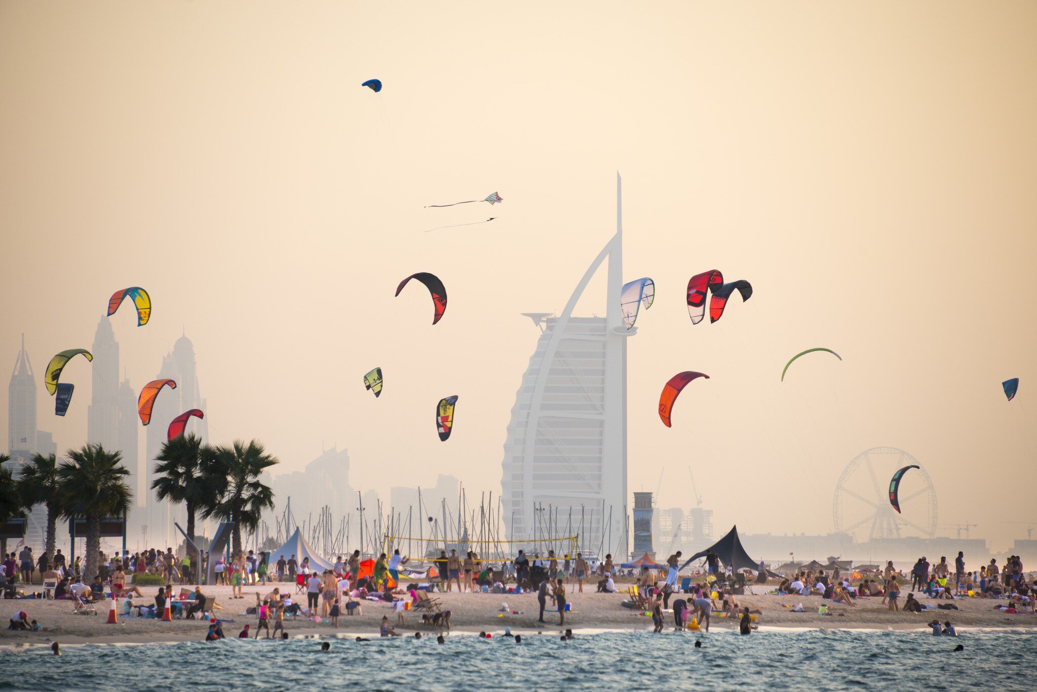 A kite beach full of kite surfers in Jumeirah with the iconic Burj Al Arab in the background.