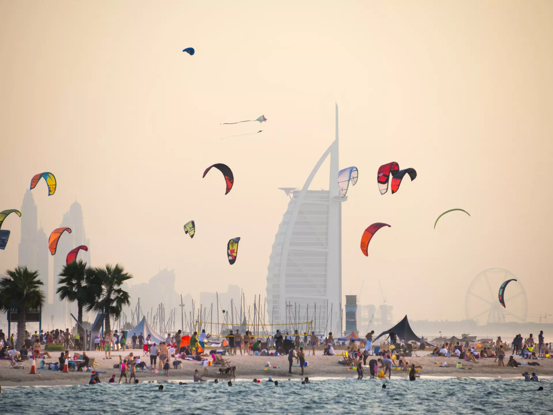 A kite beach full of kite surfers in Jumeirah with the iconic Burj Al Arab in the background.
