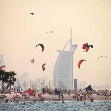 A kite beach full of kite surfers in Jumeirah with the iconic Burj Al Arab in the background.