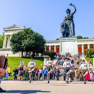 Traditional dancing group in front of the Bavaria Statue at the Octoberfest in Munich.