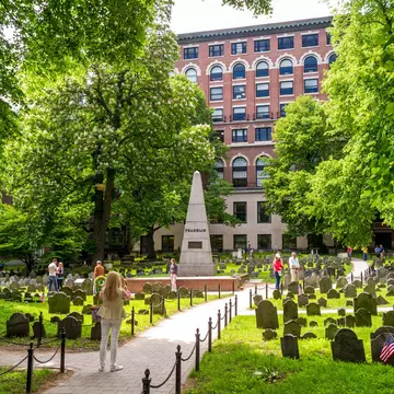 People walk about an ancient graveyard looking at the headstones