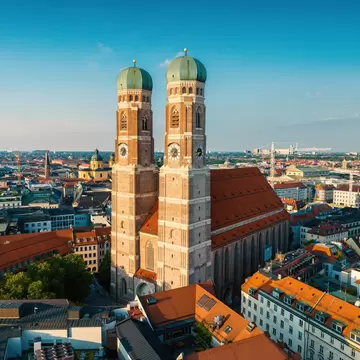 The twin domes of the Frauenkirche stand sentinel over Marienplatz in Munich, Germany on a summer evening.