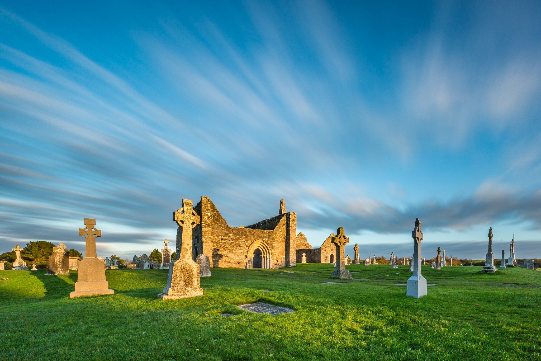 The monastery of Clonmacnoise is lighting golden in the evening sun.