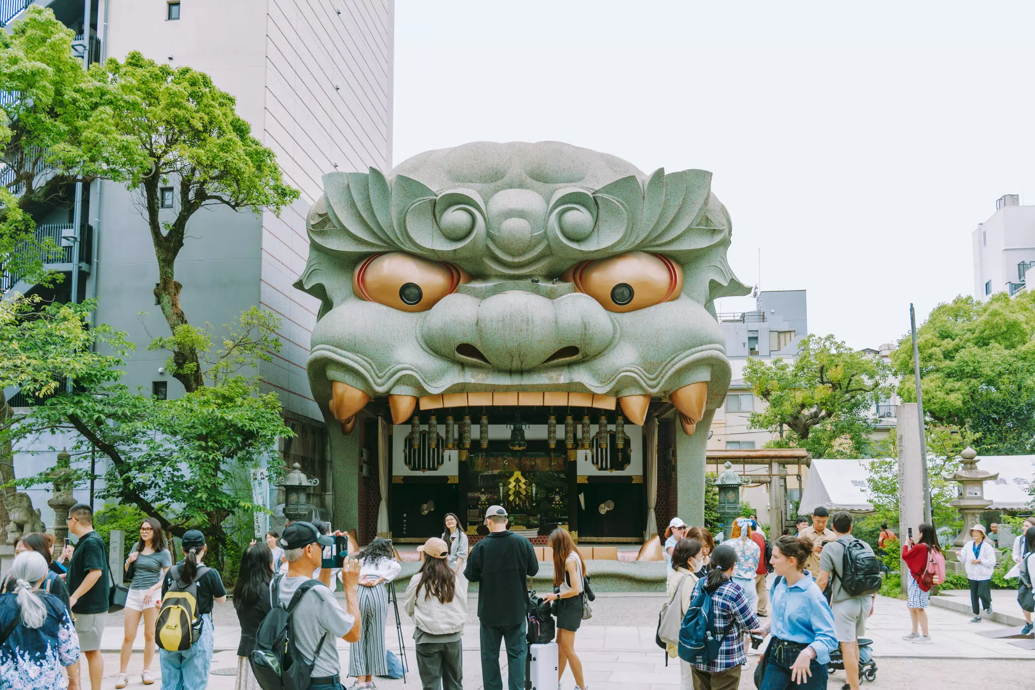 People pause outside a shrine with an entrance shaped like a lion's head.