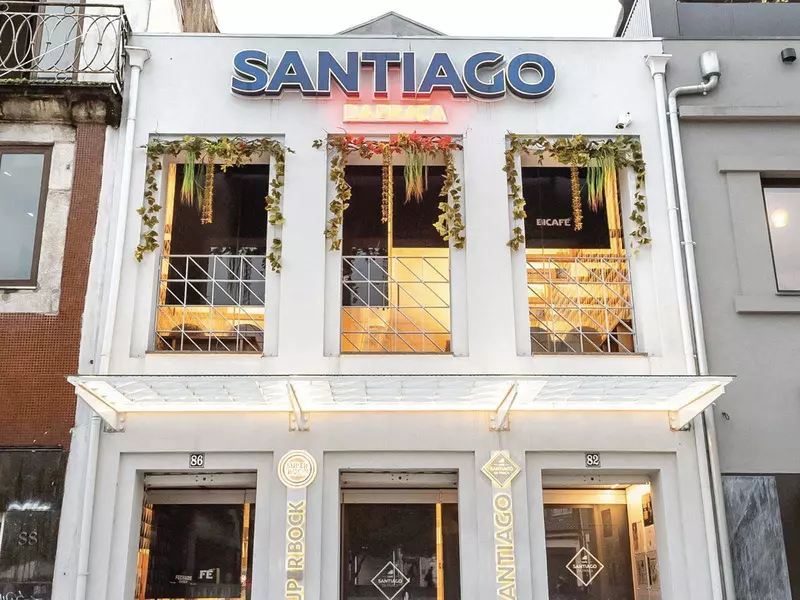 The white facade of a restaurant with big windows. Café Santiago da Praça is above the windows.