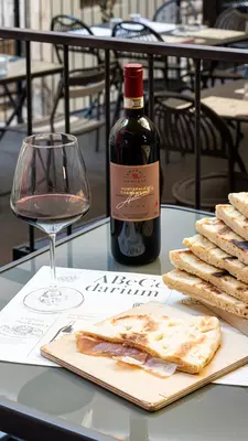 A bottle of wine and an Italian flatbread on an outdoor table at Osteria a Priori