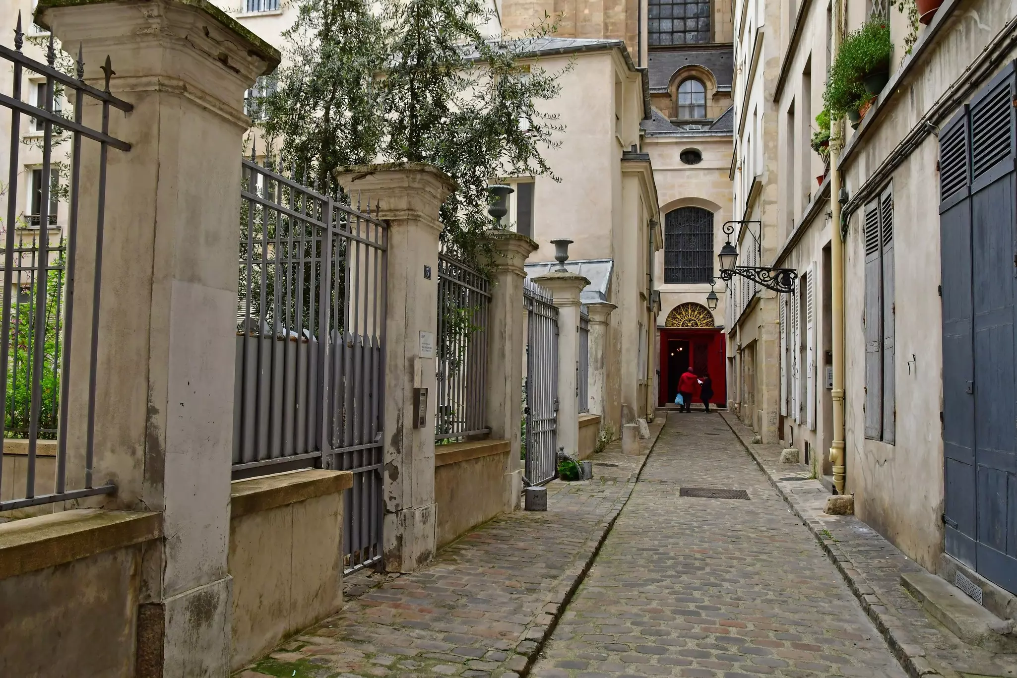 A narrow street with a gate to one side and buildings to the other.