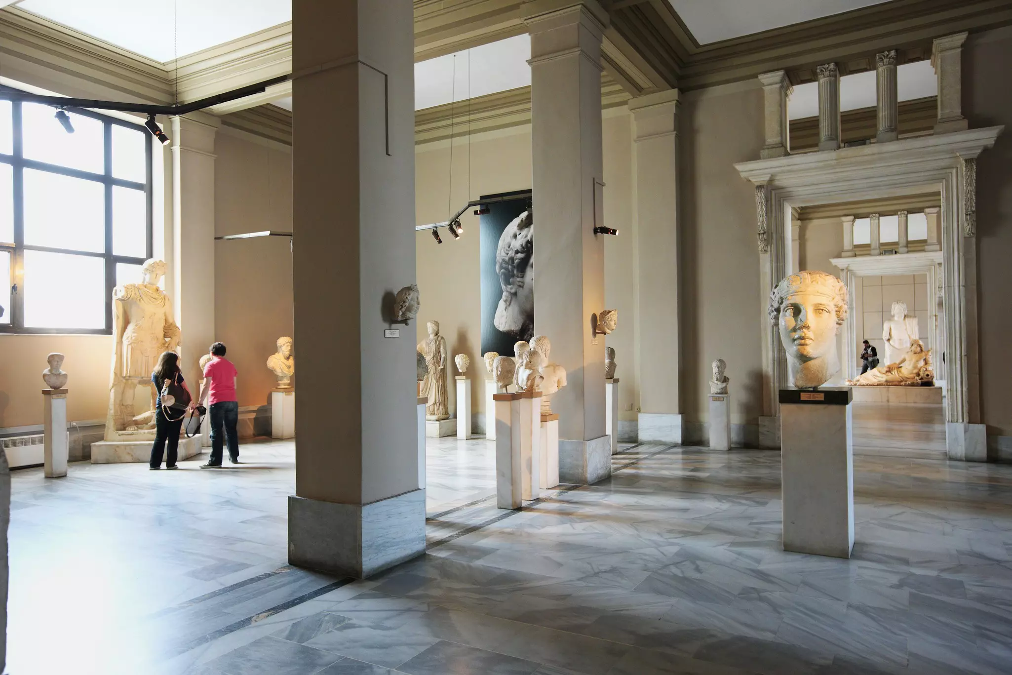People in a gallery full of Roman-era statues and art works