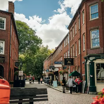 Shoppers stroll a brick-paved street lined with historic red-brick buildings in downtown Portsmouth, New Hampshire
