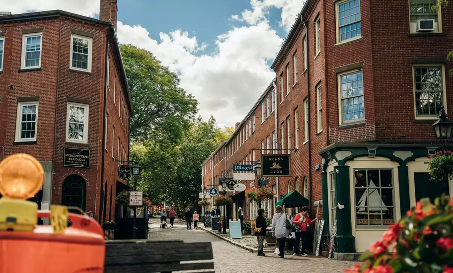 Shoppers stroll a brick-paved street lined with historic red-brick buildings in downtown Portsmouth, New Hampshire