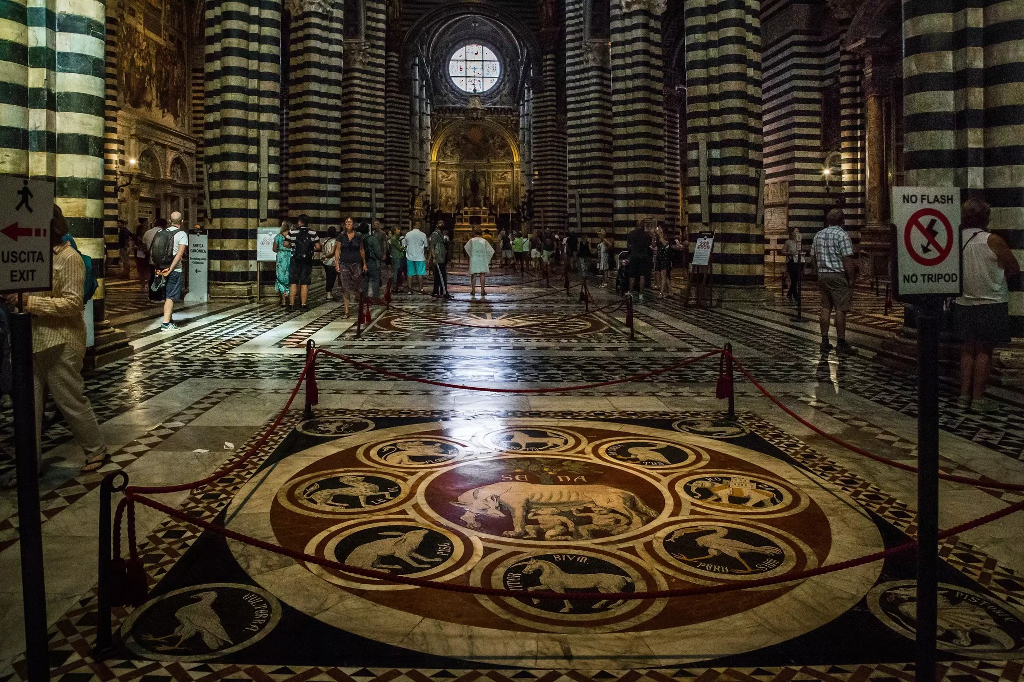 People are seen in a church with beautiful mosaic-tile floors and dramatic striped columns.