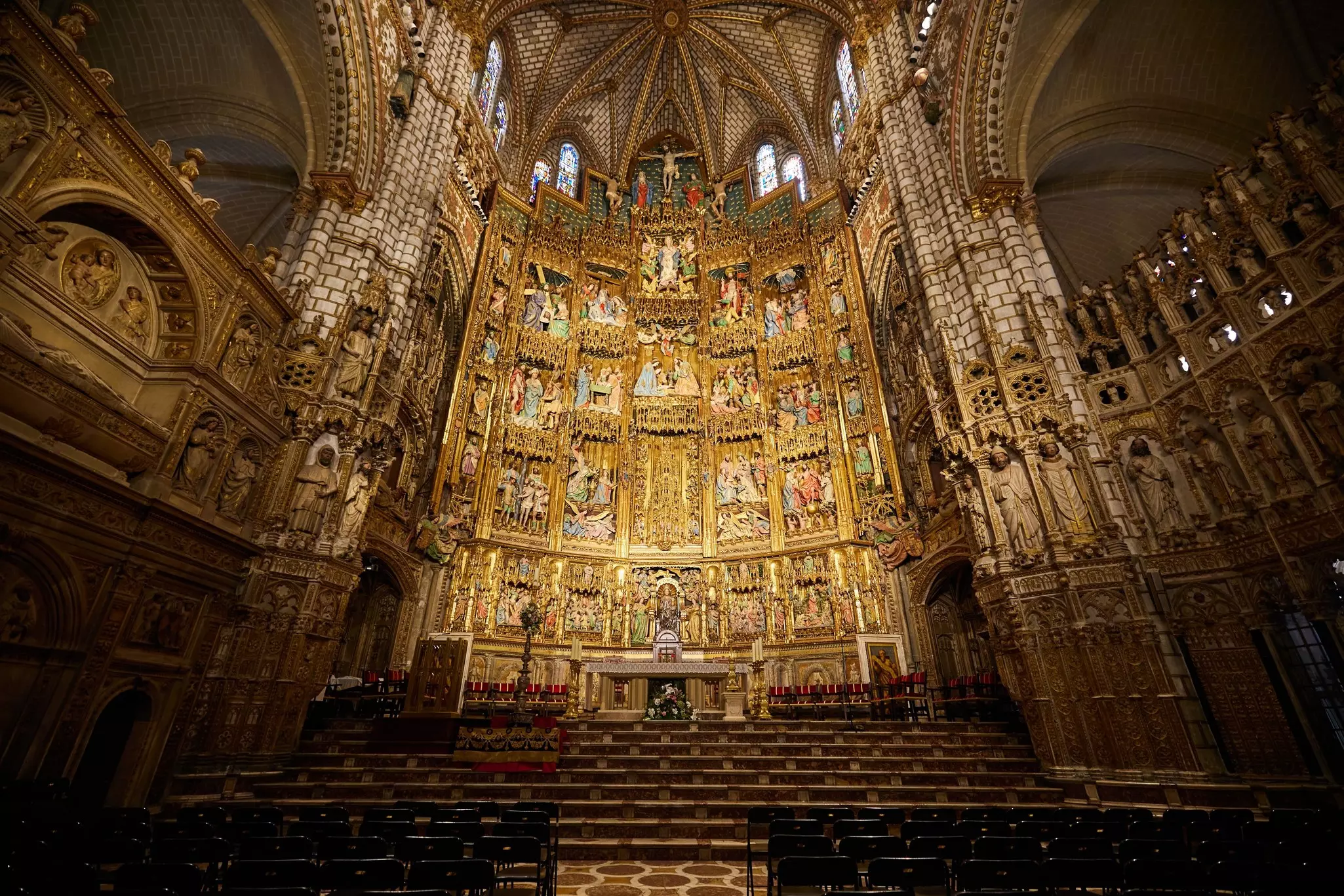 Ornate altar with gold and religious sculptures and paintings within a cathedral