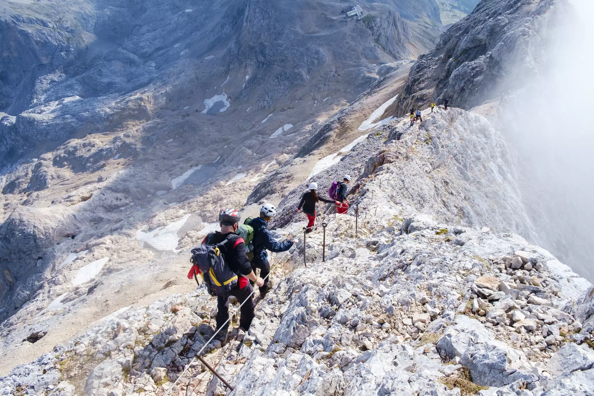 Climbers using a cable to stay stable on a craggy mountain