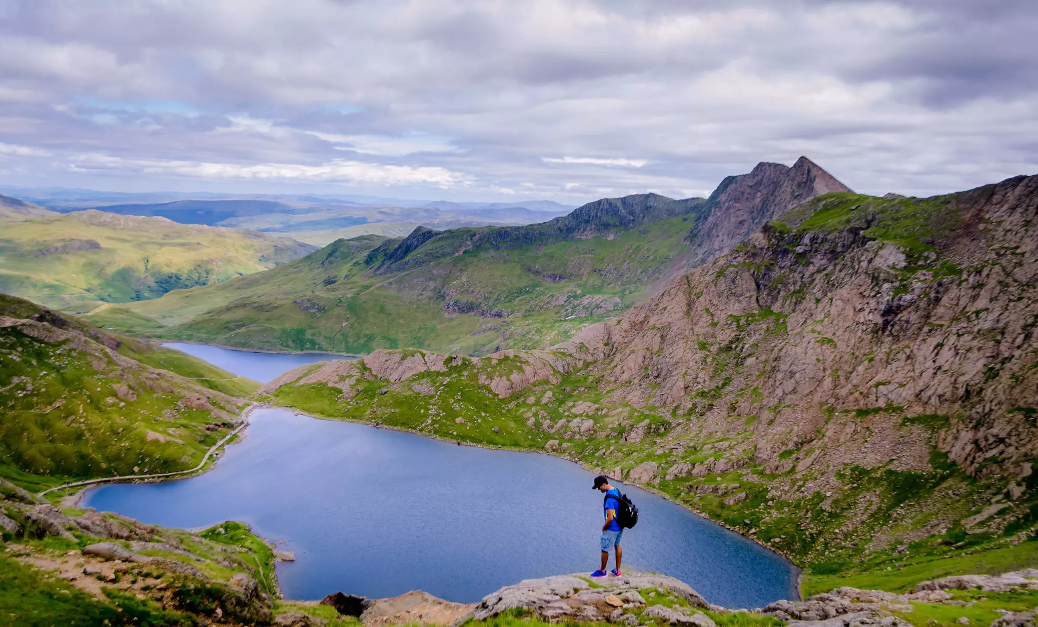 A male hiker standing above Lake Glaslyn on the summit of Snowdon mountain in Wales