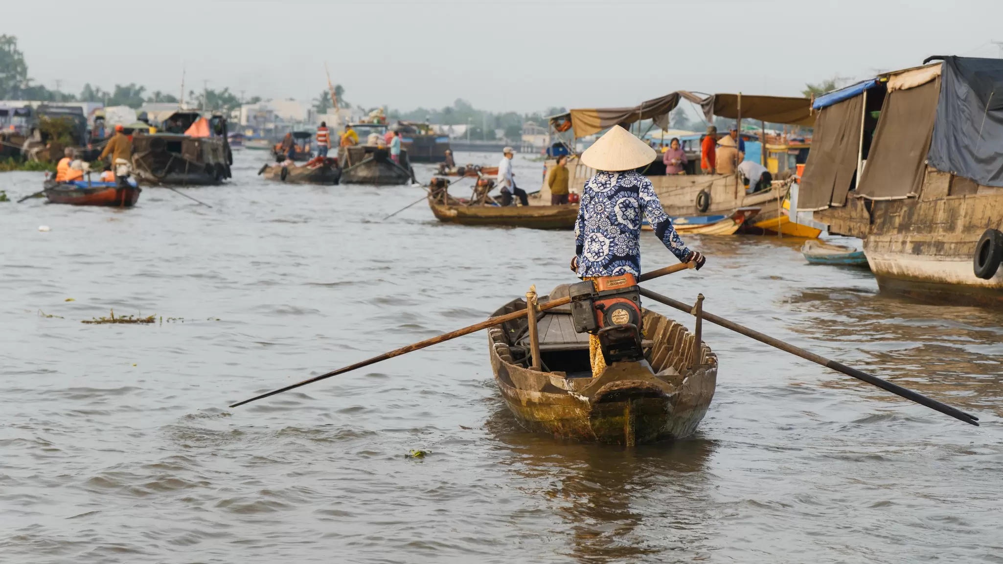 Small wooden rowing boats being piloted along the Hau River at Can Tho, Vietnam. 