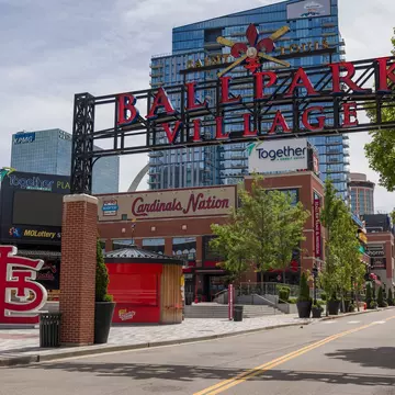 The entrance to a neighborhood with a large sign that says "Saint Louis Ballpark Village"