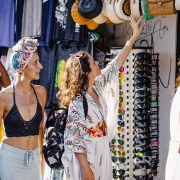 A group of friends browsing merchandise at market stalls while exploring in Bali, Indonesia