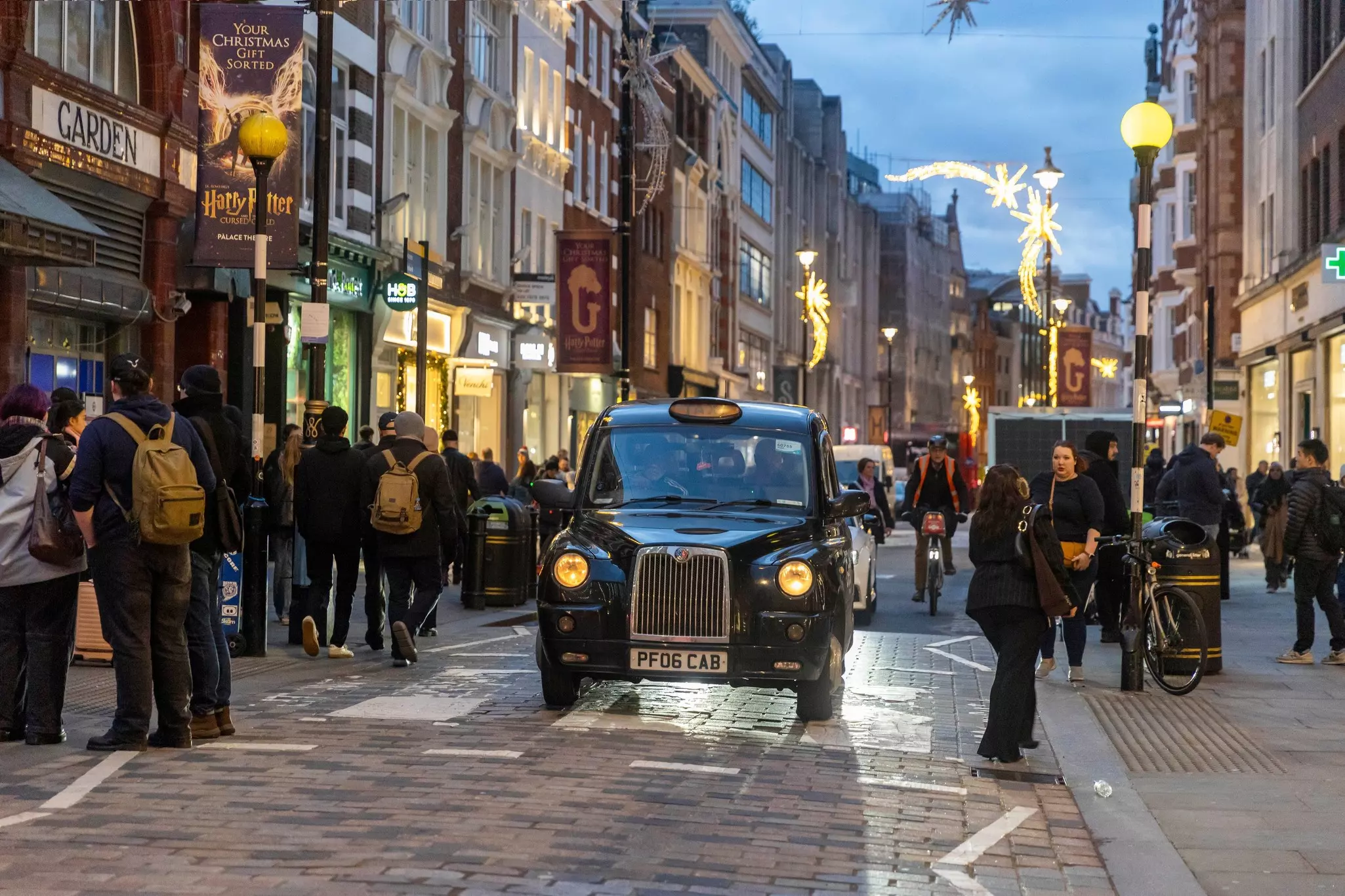 London, UK, November 22, 2024. A cab is driving down the street past Covent Garden tube station, with people rushing about their business. Dusk. Christmas illuminations., License Type: media, Download Time: 2025-01-30T23:11:53.000Z, User: sashabrady26, Editorial: true, purchase_order: 65050 - Digital Destinations and Articles, job: Lonely Planet, client: Photo haul, other: Sasha Brady