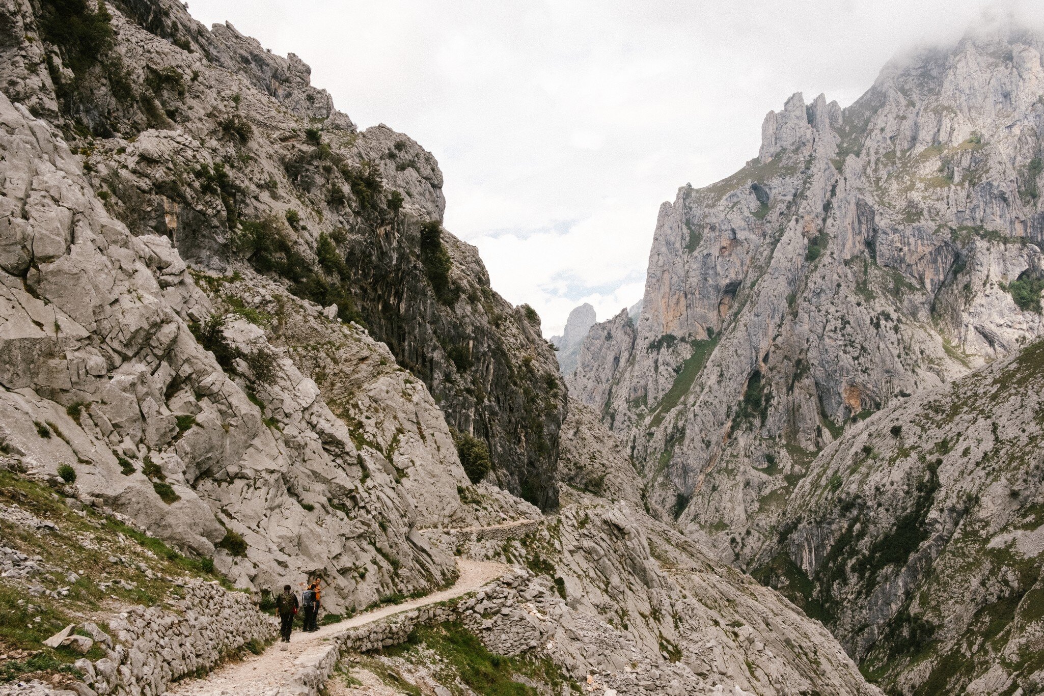 Two people walk the path of a rocky path in the Spanish mountains. 