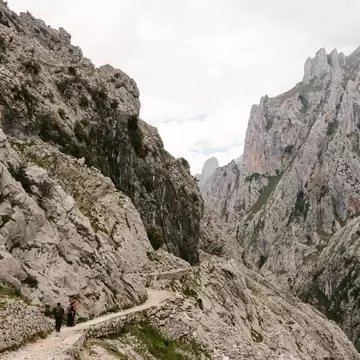 Two people walk the path of a rocky path in the Spanish mountains. 