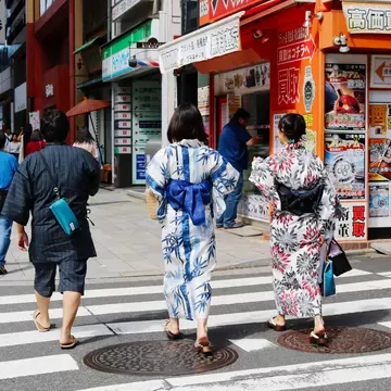 People dressed in traditional clothing walking along a street in Tokyo's Nihonbashi area on a sunny day.