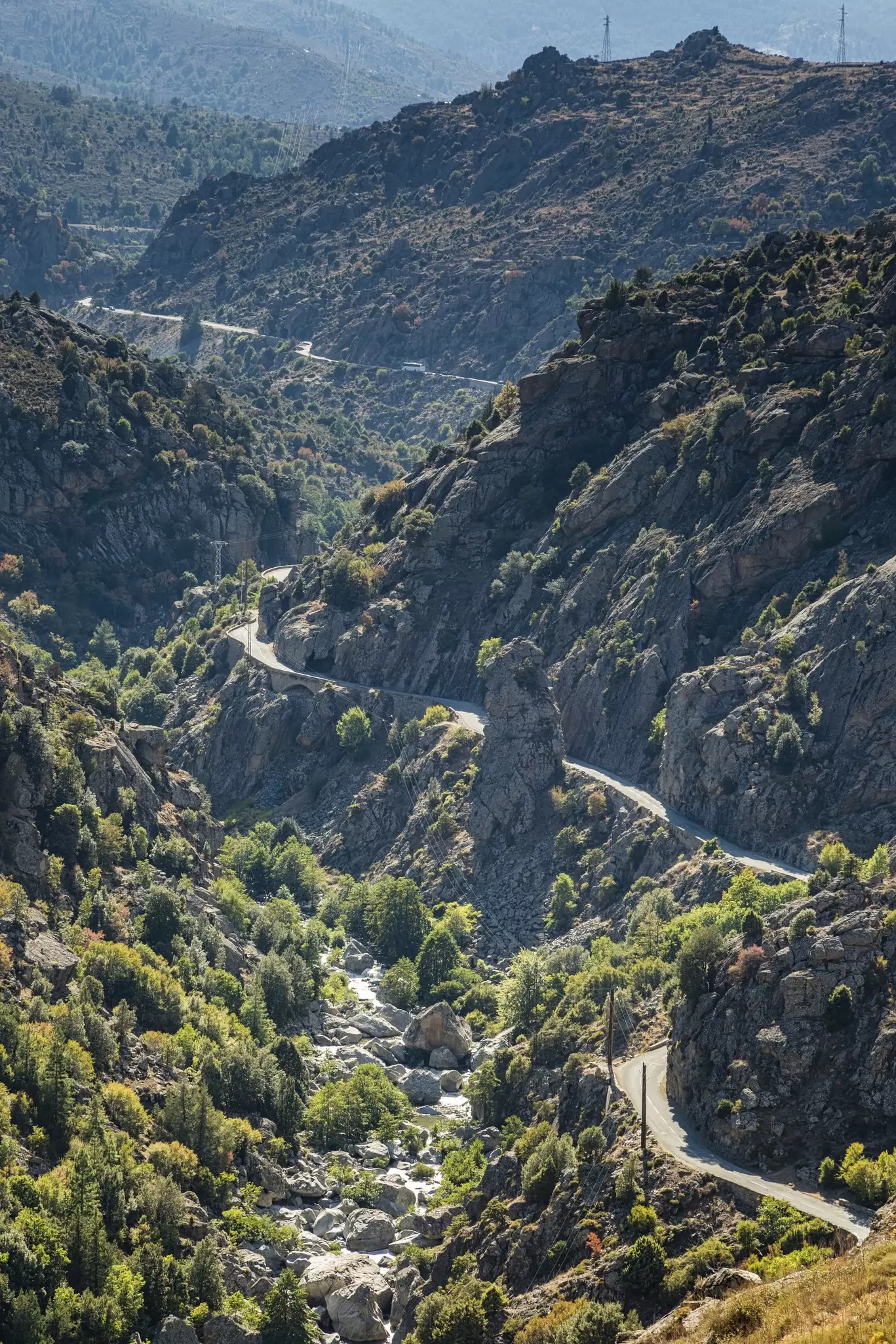 A narrow road weaves through a mountain valley clinging to the edge of cliffs: the D84 in Corsica
