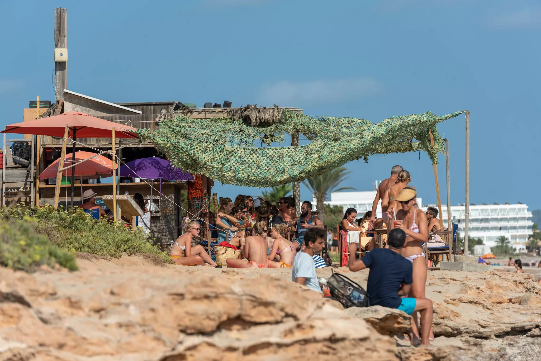 People gather at a beach bar in the sun.